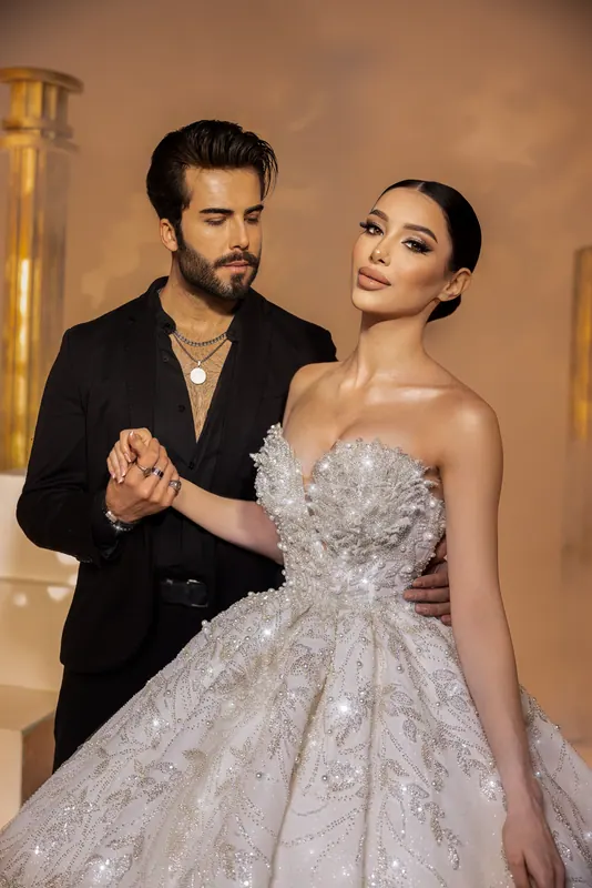 Groom holding the bride's hand, crystal ball gown