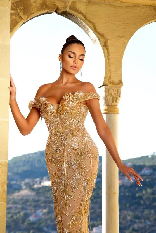 Gold beaded gown under a stone arch above the sea